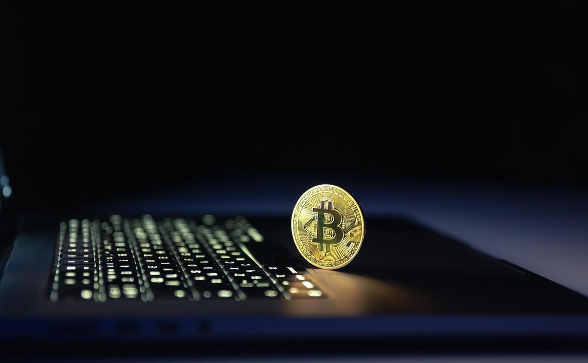 Bitcoin coin near laptop on black background Finance and crypto money concept